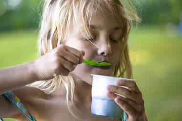 Blondes Mädchen isst Eiscreme im Einwegbecher - JFEF00960