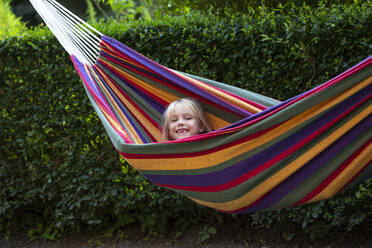 Cute girl enjoying while lying in hammock at garden - JFEF00963