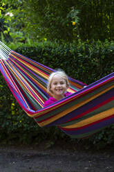 Smiling girl portrait while relaxing in hammock at garden - JFEF00964