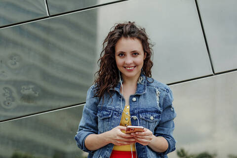 Young woman using smartphone at wall stock photo