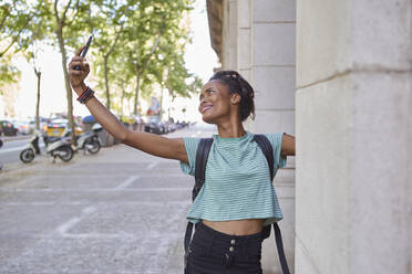 Glückliche junge Frau, die ein Selfie mit einer Säule auf dem Gehweg macht - VEGF02655