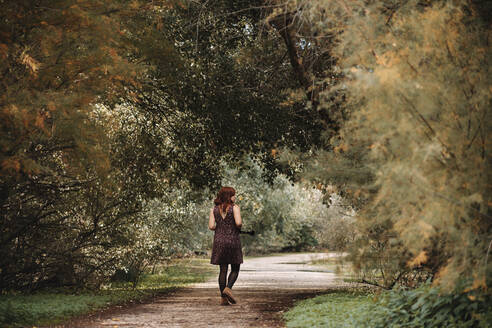 Junge Frau geht auf einem Fußweg inmitten von Pflanzen im Wald - MRRF00274
