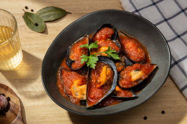 Plate of shellfish mussels cooked in Italian tomato sauce standing on kitchen table - ADSF10836