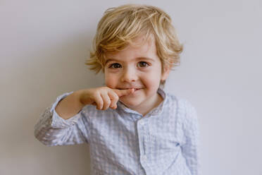 Adorable kleines Kind trägt lässig Shirt lächelnd und Blick auf die Kamera auf weißem Hintergrund des Studios - ADSF10922