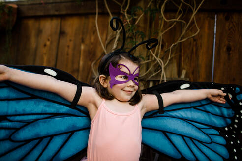 Junges Mädchen in Verkleidung breitet Schmetterlingsflügel aus - CAVF88079