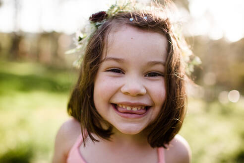 Nahaufnahme eines jungen Mädchens mit Blumenkrone, das albern ist - CAVF88084