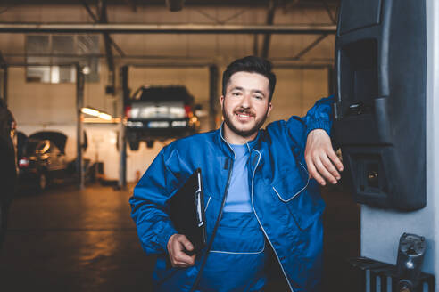 Portrait of a positive car mechanic in a garage - CAVF88118