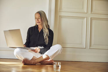 Reife Frau benutzt Laptop, während sie zu Hause sitzt - MCF01050