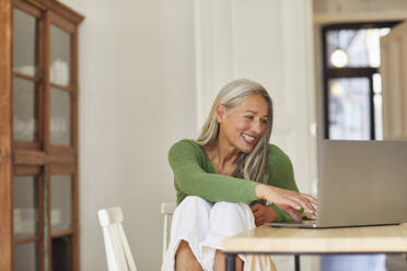 Smiling businesswoman using laptop at home - MCF01073