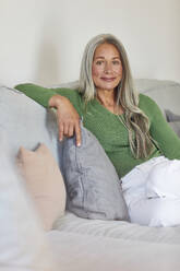 Smiling woman on sofa at home - MCF01083