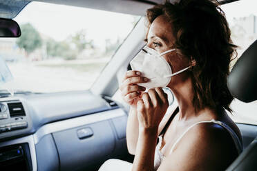 Frau mit Gesichtsschutzmaske im Auto während COVID-19 - EBBF00546
