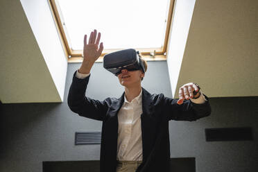 Businesswoman gesturing while wearing virtual reality simulator headset at office - VPIF02682