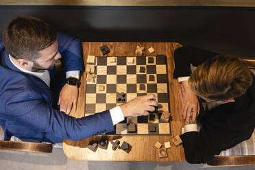 Männlicher und weiblicher Unternehmer spielen Schach im Kreativbüro - VPIF02692