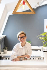 Lächelnde Unternehmerin sitzt am Schreibtisch in einer Büro-Cafeteria - VPIF02734