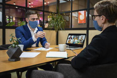 Männliche und weibliche Unternehmer tragen Masken bei der Strategieplanung im Sitzungssaal während einer Pandemie - VPIF02739