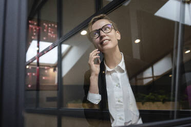 Schöne Geschäftsfrau, die mit dem Handy telefoniert, während sie im Büro wegschaut - VPIF02764
