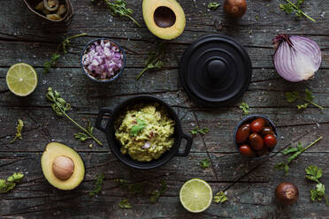 Top view of various fresh ingredients placed on lumber table near pot with yummy guacamole - ADSF10972