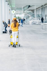 Junge Frau schiebt Gepäckwagen am Flughafen - ADSF10987