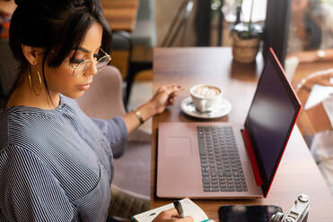 Girl having a coffee while working in a cozy environment - CAVF88268