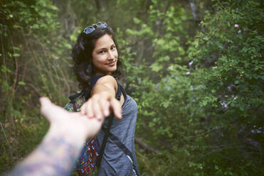 Porträt einer glücklichen jungen Frau, die die Hand ihres Freundes hält, während sie den Berg hinuntergeht - CAVF88280
