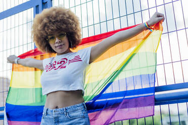 Woman holding her gay pride flag on a bridge - CAVF88286