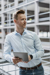 Confident businessman with digital tablet looking away in city - DIGF12805