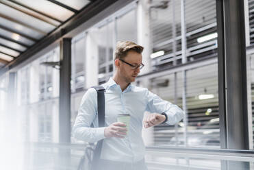 Businessman with coffee checking the time in city - DIGF12814