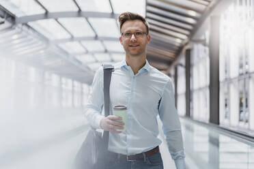 Businessman with coffee walking in city - DIGF12815