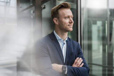 Confident entrepreneur with arms crossed looking away in city - DIGF12834