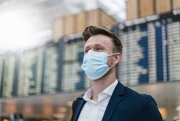 Businessman wearing face mask while looking away in city - DIGF12853