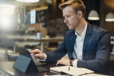 Geschäftsmann mit digitalem Tablet am Tisch in einem Café - DIGF12868