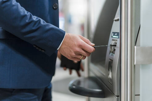 Close-up of businessman withdrawing money at an ATM - DIGF12875