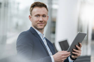 Confident businessman with digital tablet in city - DIGF12885