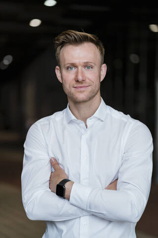 Confident businessman with arms crossed standing in city stock photo