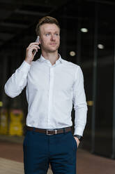 Businessman talking on smart phone in city - DIGF12900