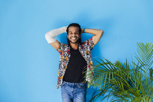 Smiling man with fractured arm posing against blue background - MRAF00579