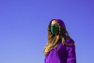 Teenager-Mädchen mit Kapuzenpulli und Gesichtsschutzmaske mit Fliegenaufkleber auf der Nase - ERRF04220