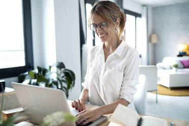 Smiling freelancer working over laptop at home - JSRF01012