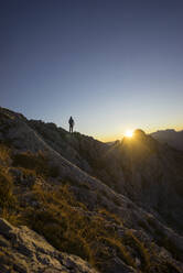 Rückansicht eines Wanderers, der bei Sonnenaufgang auf einem Aussichtspunkt steht, Gimpel, Tirol, Österreich - MALF00061