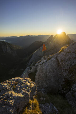 Rear view of female hiker on viewpoint during sunrise, Gimpel, Tyrol, Austria stock photo