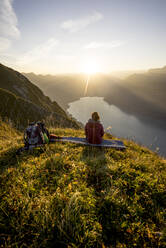 Wanderin auf Aussichtspunkt sitzend bei Sonnenuntergang, Augstmatthorn, Schweiz - MALF00076