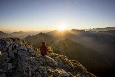 Wanderin auf einem Aussichtspunkt sitzend bei Sonnenuntergang, Hochplatte, Bayern, Deutschland - MALF00081