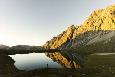 Hiker standing at Lake Kogelsee in the evening, Tyrol, Austria - MALF00121