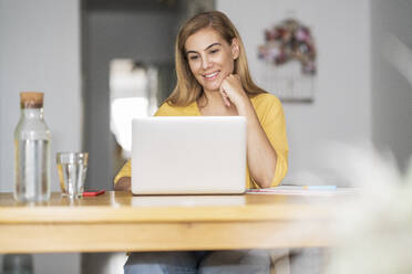 Smiling mature woman using laptop at home - JSMF01682