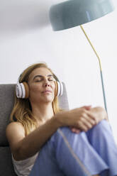 Ältere Frau hört zu Hause Musik über Kopfhörer - JSMF01695