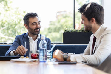 Lächelnde Geschäftsleute diskutieren während eines Treffens im Restaurant - JSRF01018