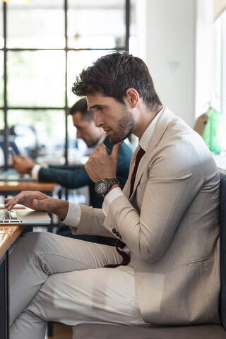 Businessman thinking while using laptop in restaurant stock photo