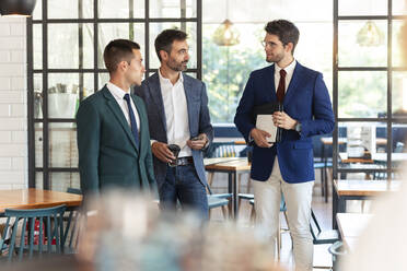 Businessmen talking while standing in restaurant - JSRF01043