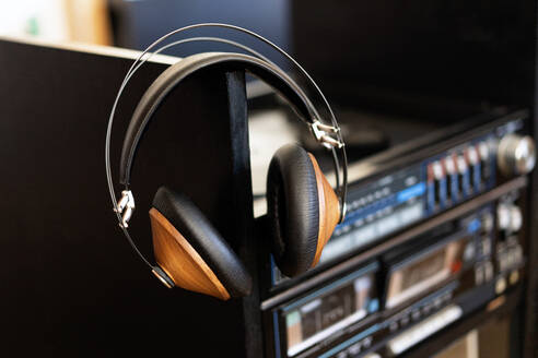 Vintage-Kopfhörer aus Holz liegen auf einem schwarzen Vinyl in einem Plattenspieler - ADSF10996