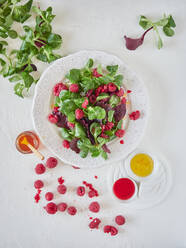 Von oben helle Zusammensetzung der leckeren appetitlichen Salat mit reifen Himbeeren grünen Spinat und aromatische Sauce auf weißem Hintergrund - ADSF11020
